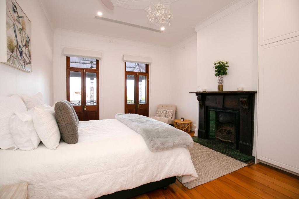 Dormitorio blanco con cama y chimenea en The Wandering Grape, en Mudgee