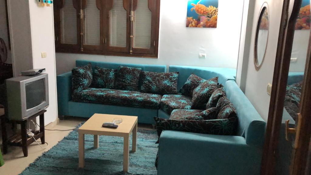 a living room with a blue couch and a table at Sunny sky in Quseir