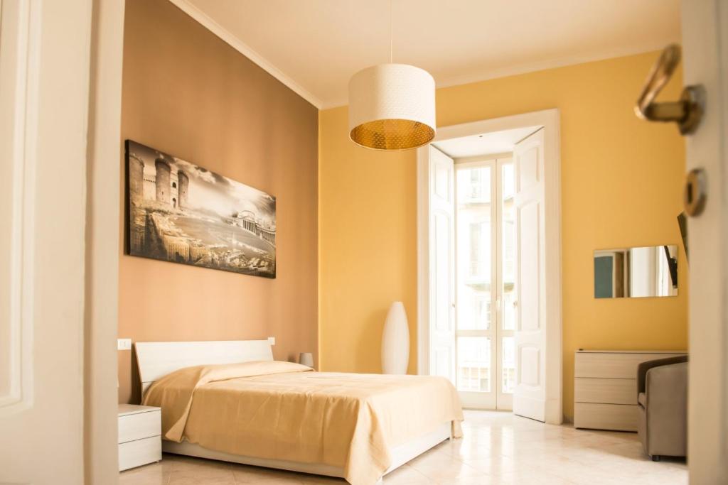 una camera da letto con pareti gialle, un letto e una finestra di Maria Marì house a Napoli