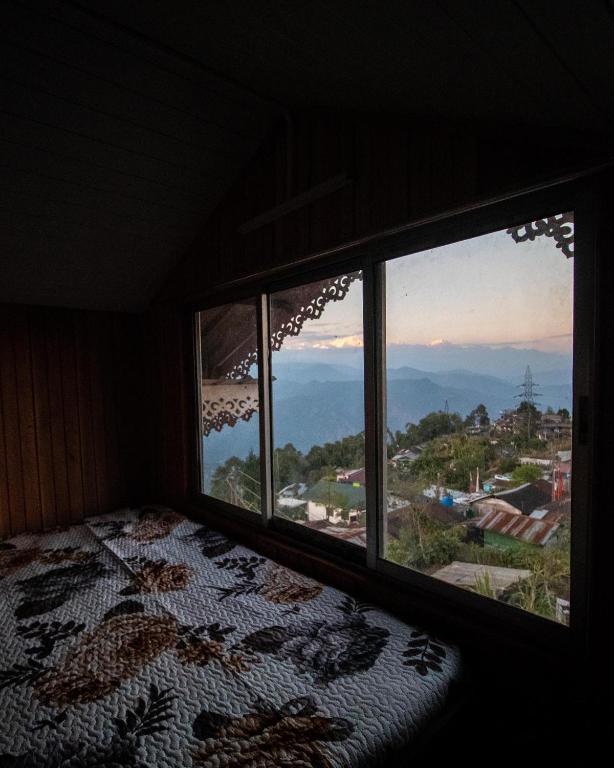 ein Schlafzimmer mit einem Bett und einem großen Fenster in der Unterkunft MiakaHillsDarjeeling in Darjeeling