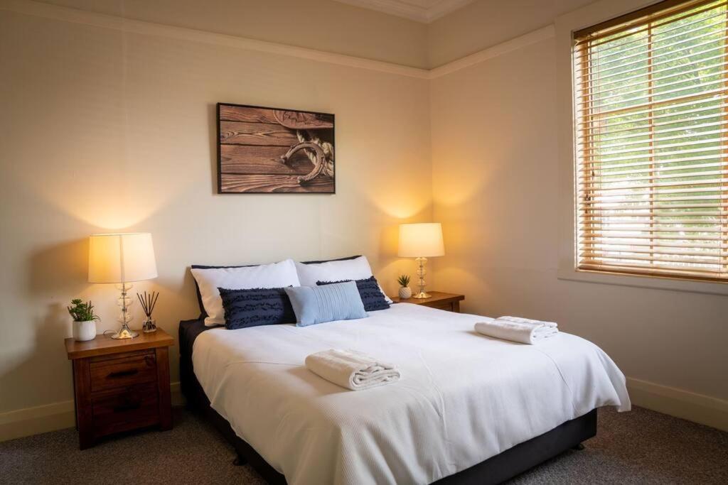 1 dormitorio con 1 cama blanca grande y 2 lámparas en Blayney Retreat-Central & Comfortable, en Blayney