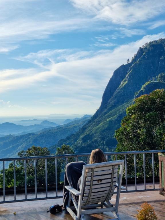 a person sitting in a chair looking at the mountains at Hilltop Guest House in Ella