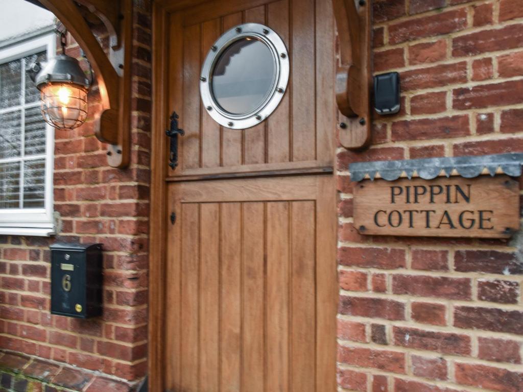 una puerta de madera con un espejo en una pared de ladrillo en Pippin Cottage en Bures Saint Mary