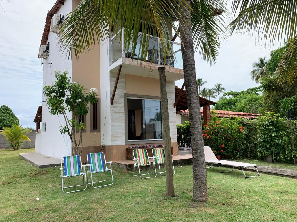 a house with chairs and a bench in the yard at Casa D'Jhú in Vera Cruz de Itaparica