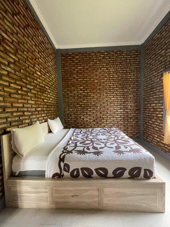 a bed in a room with a brick wall at Panji Hostel in Sukasada