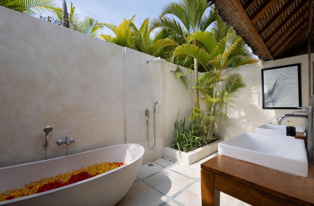 ein Badezimmer mit einer Badewanne, einem Waschbecken und Palmen in der Unterkunft Villa Markisa Echo Beach in Canggu