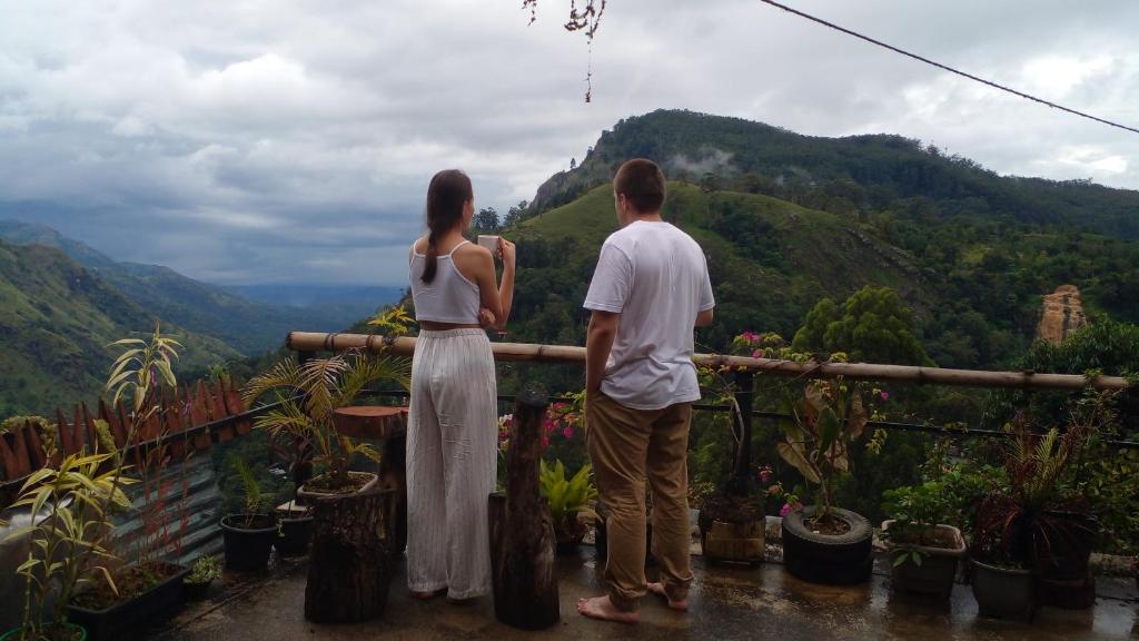 a man and woman standing on a balcony looking at the mountains at Secret View Homestay Ella in Ella