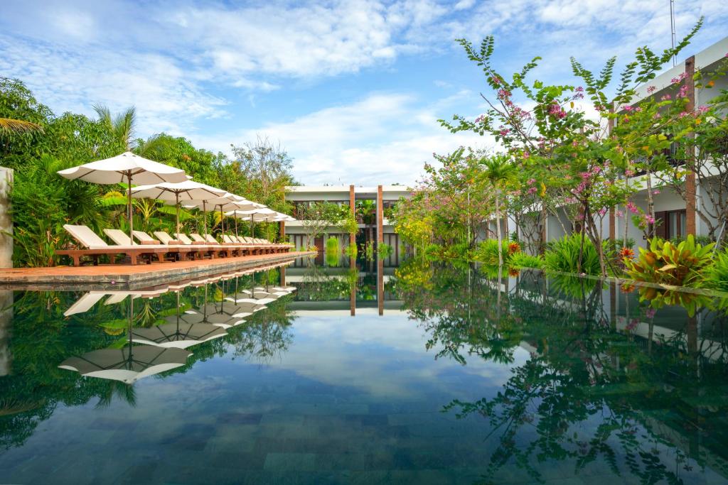 Khmer House Resort في سيام ريب: مسبح في منتجع فيه كراسي ومظلات