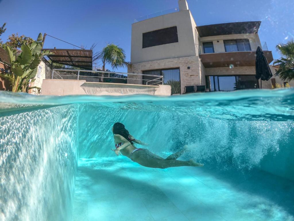 una mujer nadando en el agua en una piscina en Almi-Cove Hilltop Villas, en Almyrida