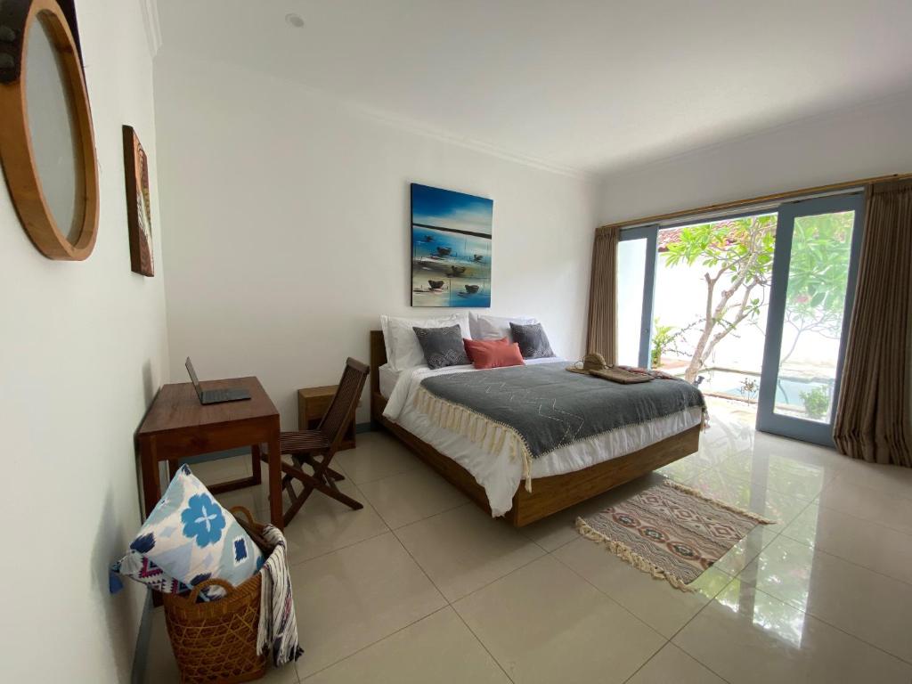 a bedroom with a bed and a desk and a window at Kubuwatu Boutique Accommodation in Gili Trawangan