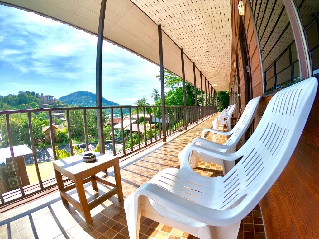 a balcony with white lounge chairs and a table at JR&GYM Resort in Phi Phi Don