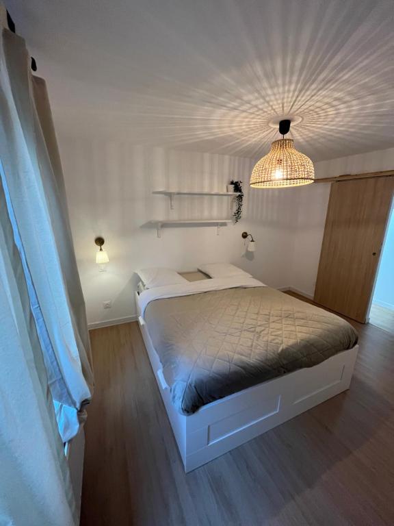 - une chambre blanche avec un lit et un lustre dans l'établissement Grande Maison Métropole Lilloise, à Seclin