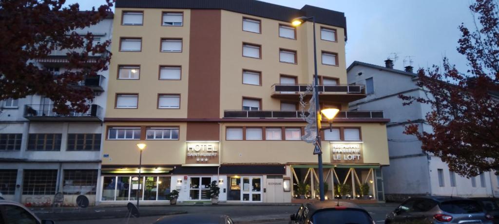 um edifício alto com uma luz de rua em frente em Hôtel Saint-Hubert em Saint-Claude