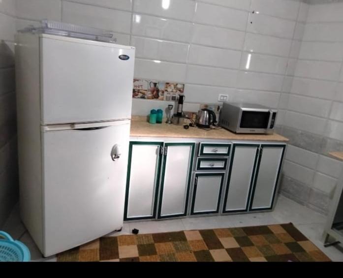 La cuisine est équipée d'un réfrigérateur blanc et d'un four micro-ondes. dans l'établissement دمياط الجديدة, à Dumyāţ al Jadīdah