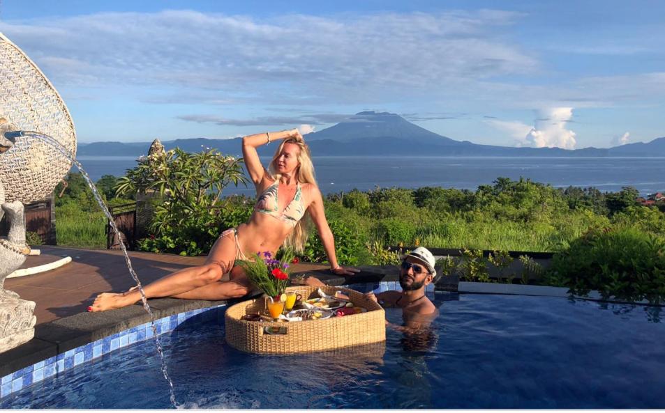 un hombre y una mujer sentados en una piscina en Reynten Hill Resort en Nusa Penida