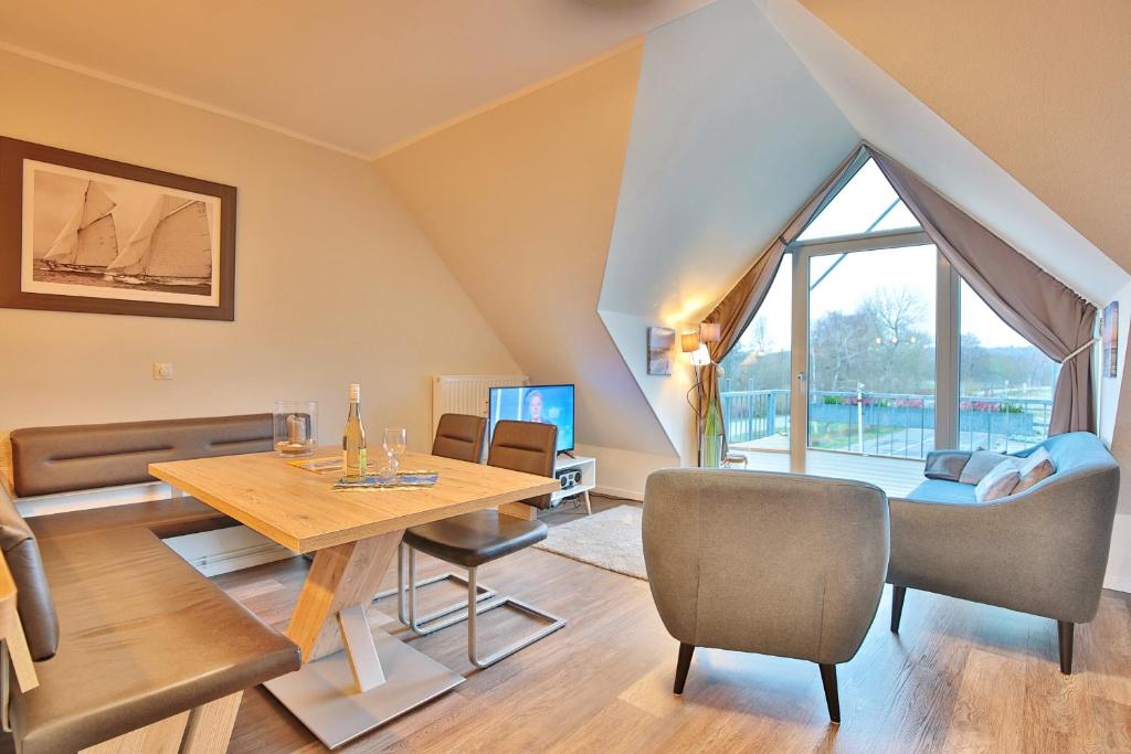 sala de estar con mesa, sillas y ventana grande en Strandduene Stranddüne Appartement 23, en Haffkrug