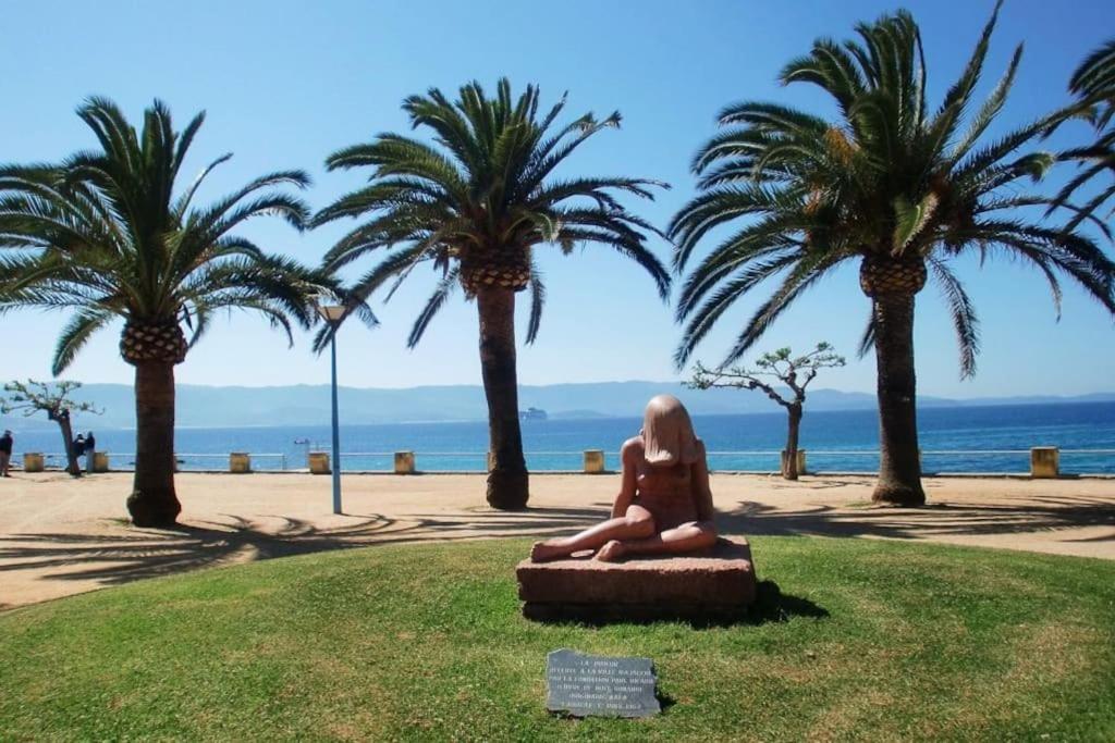 une statue d'une femme assise sur un banc à côté des palmiers dans l'établissement Bel F2 près de la plage, à Ajaccio