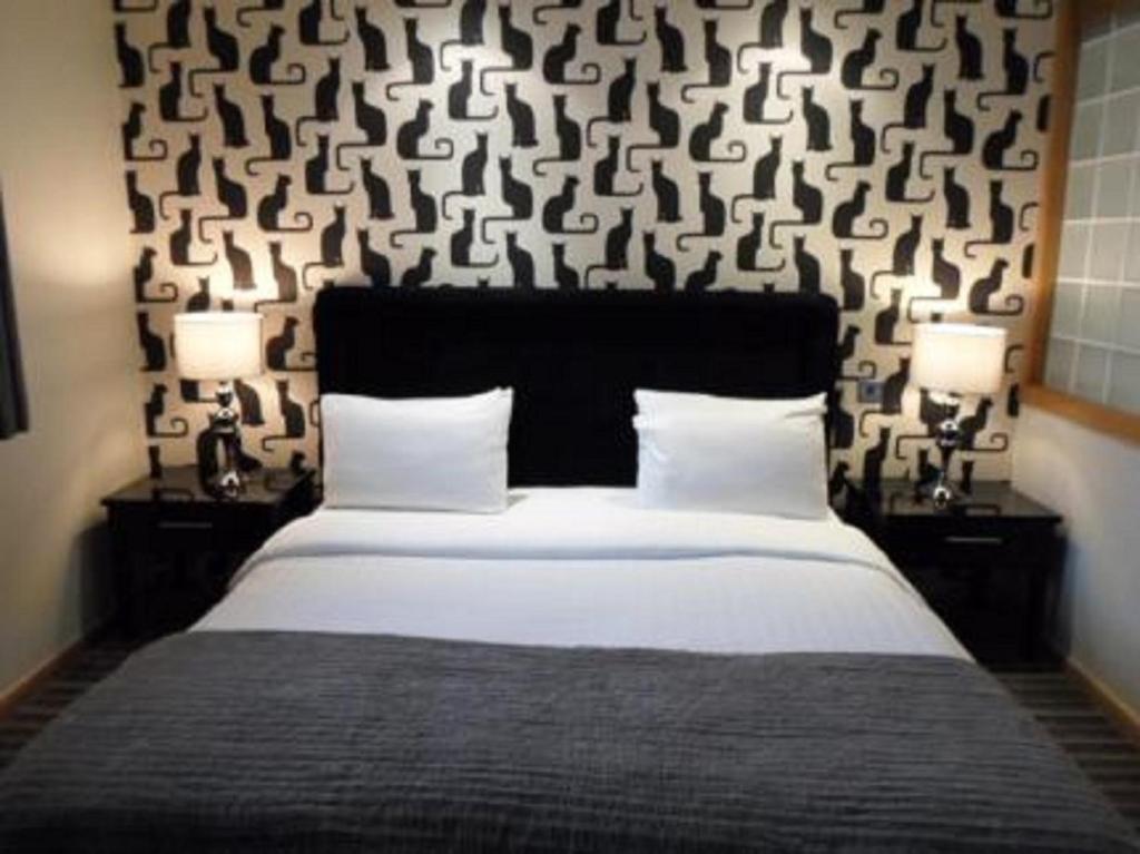 a bedroom with a large bed with two nightstands and two lamps at Cheshire Cat in Nantwich