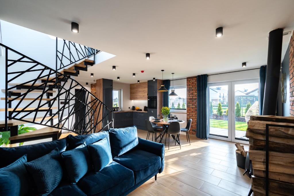 ein Wohnzimmer mit einem blauen Sofa und einer Treppe in der Unterkunft Family Resort Ustka - Domki dwupoziomowe z basenem in Ustka