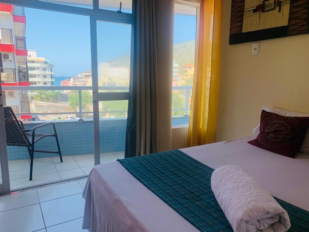 1 dormitorio con cama y vistas a un balcón en Apprainha top, en Arraial do Cabo