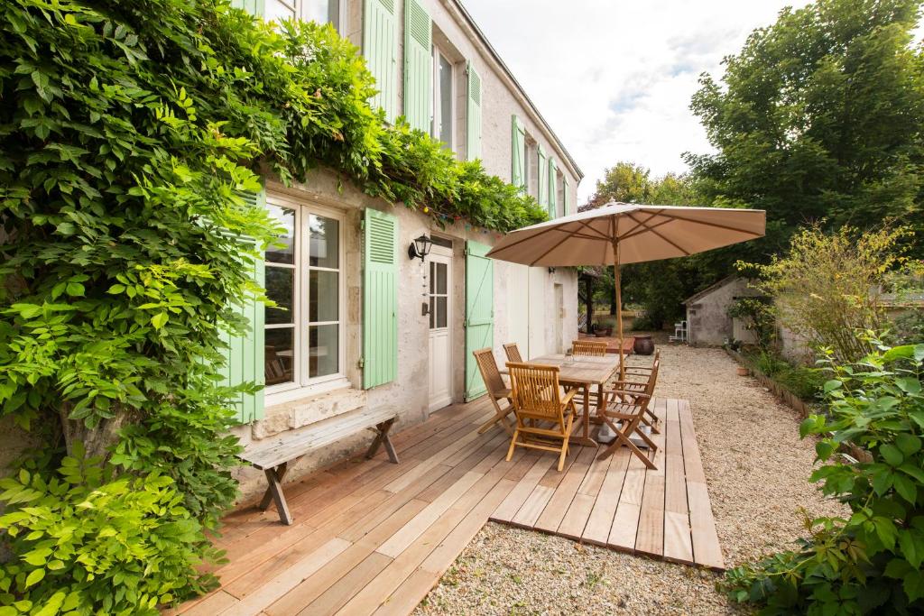 une terrasse en bois avec une table et un parasol dans l'établissement le Jardin de Josnes, à Josnes