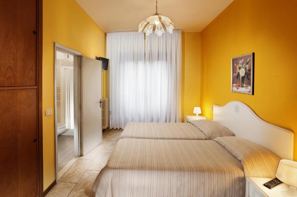 two beds in a bedroom with yellow walls at Hotel La Querceta in Montecatini Terme