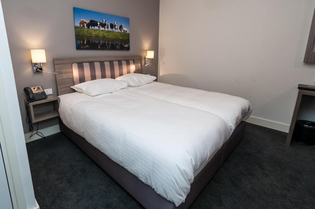 1 dormitorio con 1 cama grande con sábanas blancas en Hotel Fine Harmony, en Ámsterdam