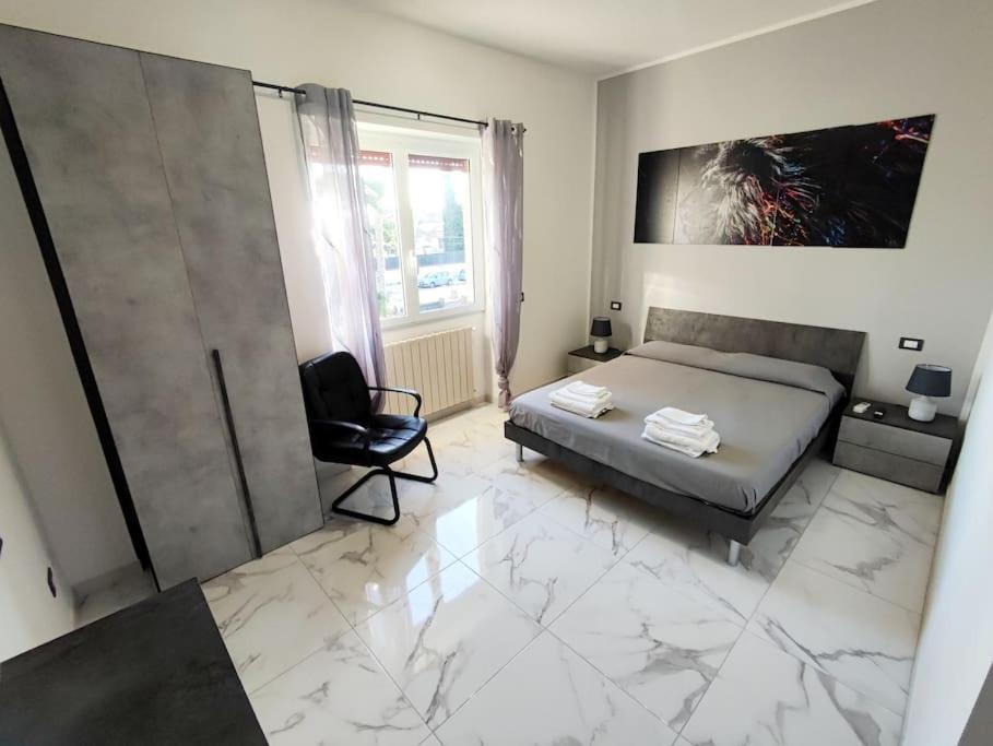 a bedroom with a king sized bed and a chair at Intero Appartamento Casa Vacanze ''il Pino'' Roma in Infernetto