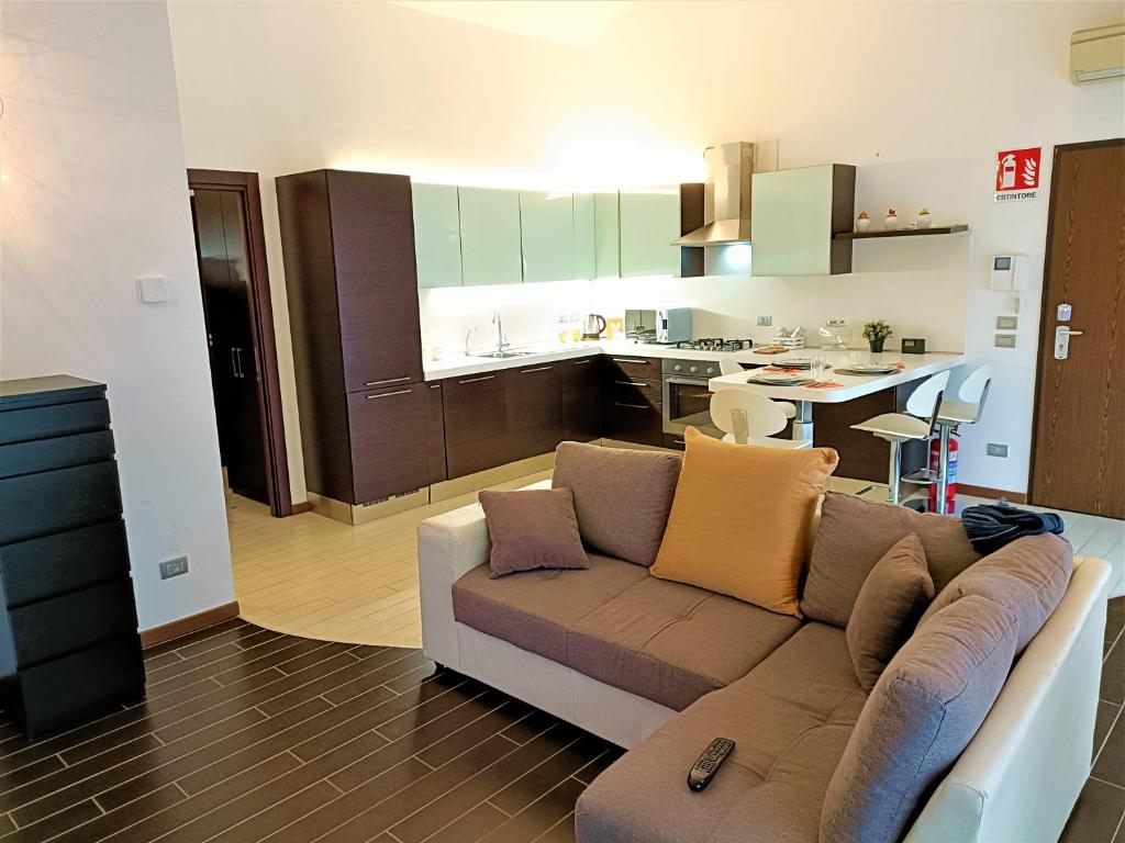 een woonkamer met een bank en een keuken bij Bareggio Comfort Apartment in Bareggio