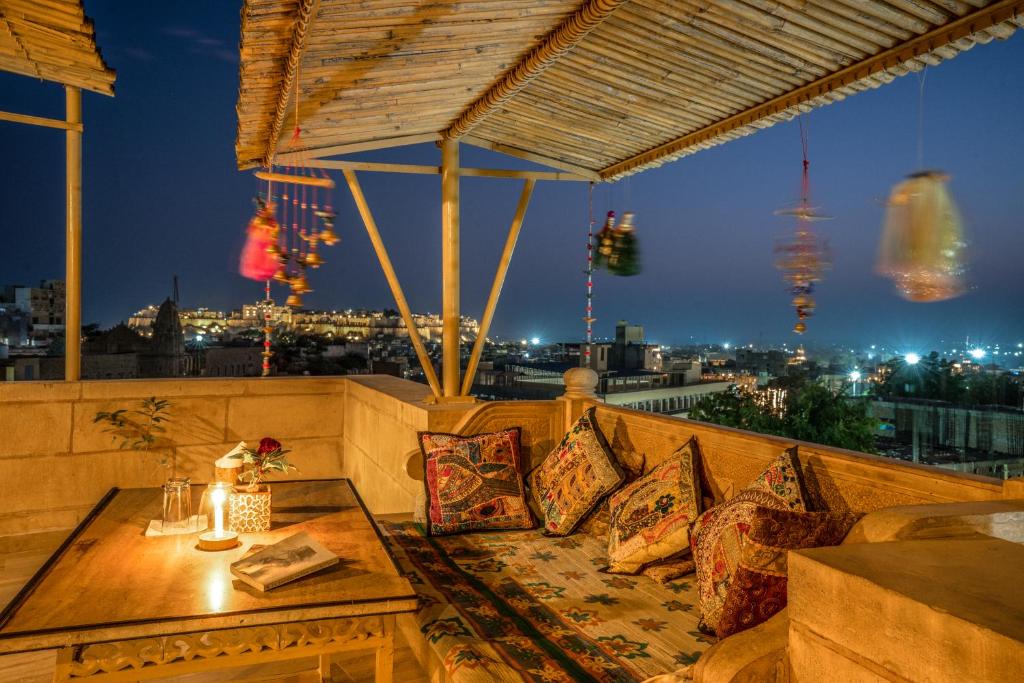 eine Terrasse mit einem Tisch und Kissen auf dem Balkon in der Unterkunft Hotel The Silk Route in Jaisalmer