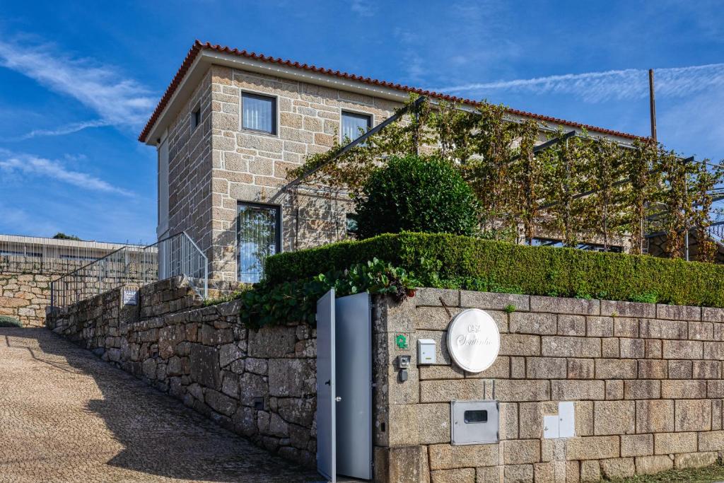 um edifício de tijolos com uma parede de pedra ao lado de uma cerca em Casa do Soutinho em Alvarenga