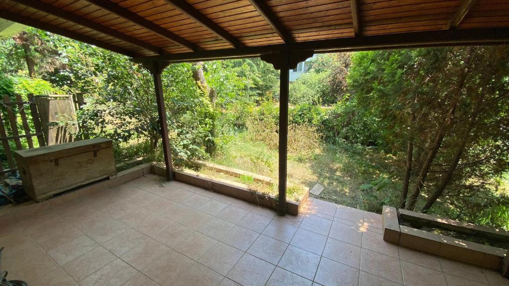 a screened porch with a bench and a view of a forest at Feel the nature near to Viaport marina in Tuzla