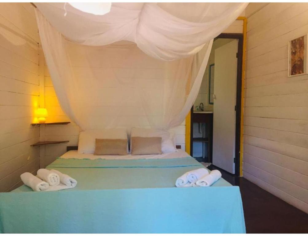 1 dormitorio con 1 cama con toallas en Quinta do Cajú, en Isla de Boipeba