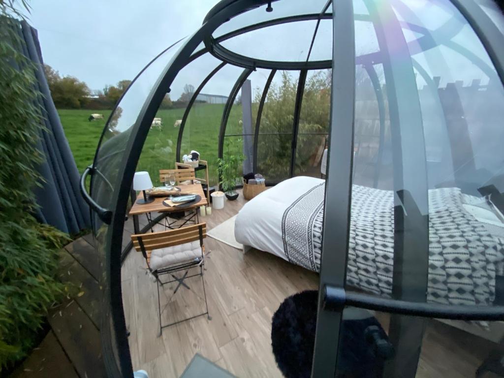 uma cama e uma mesa num deque numa tenda em Home Sweet Dôme in Bouillon em Noirefontaine