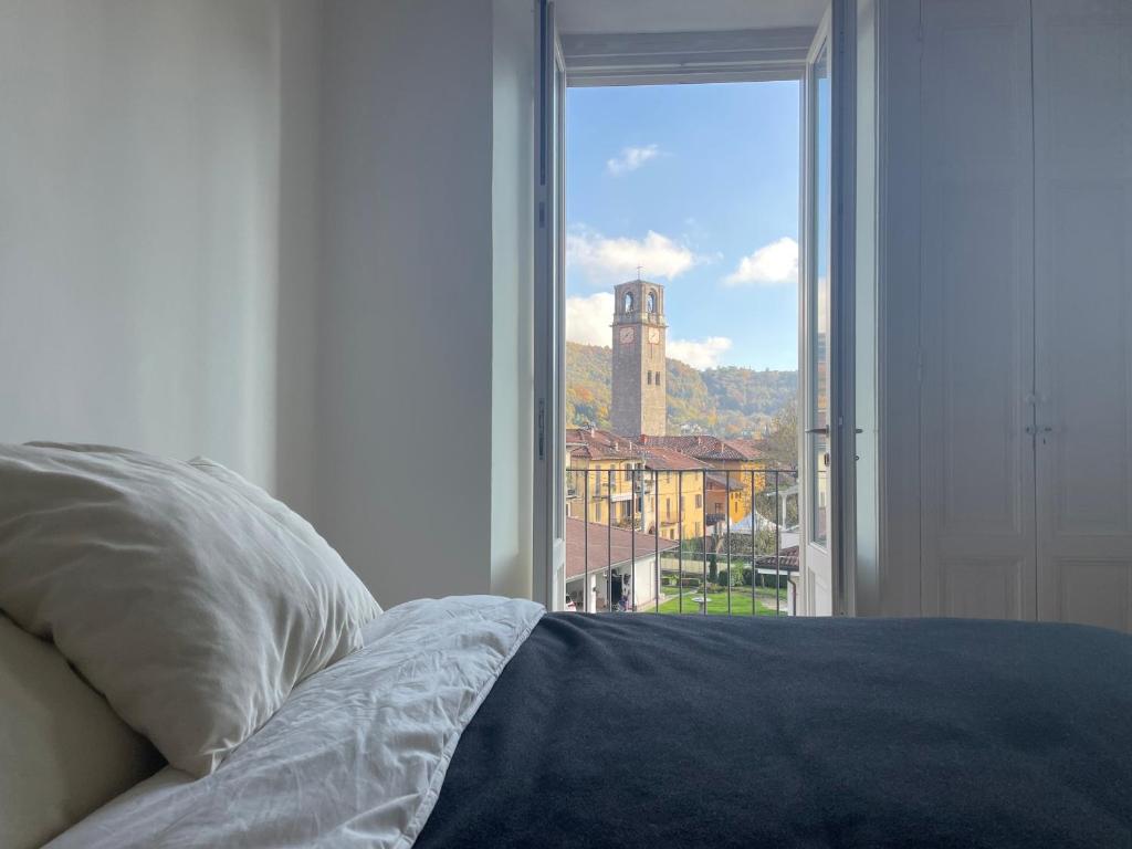 een slaapkamer met een bed en een raam met een klokkentoren bij La vista sul campanile in Andorno Micca