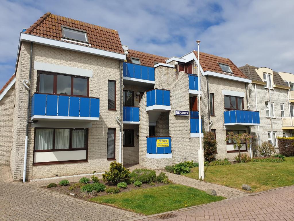 an apartment building with blue balconies on a street at Appartementen Beatrix in De Koog