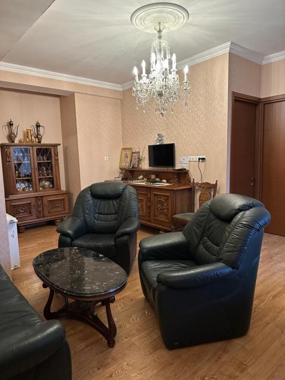 a living room with two chairs and a chandelier at Sun Apartment in Tbilisi City