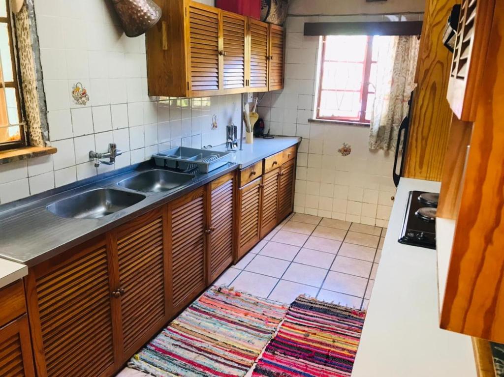 uma cozinha com armários de madeira e um lavatório em LRN Brackenfell Homestay na Cidade do Cabo