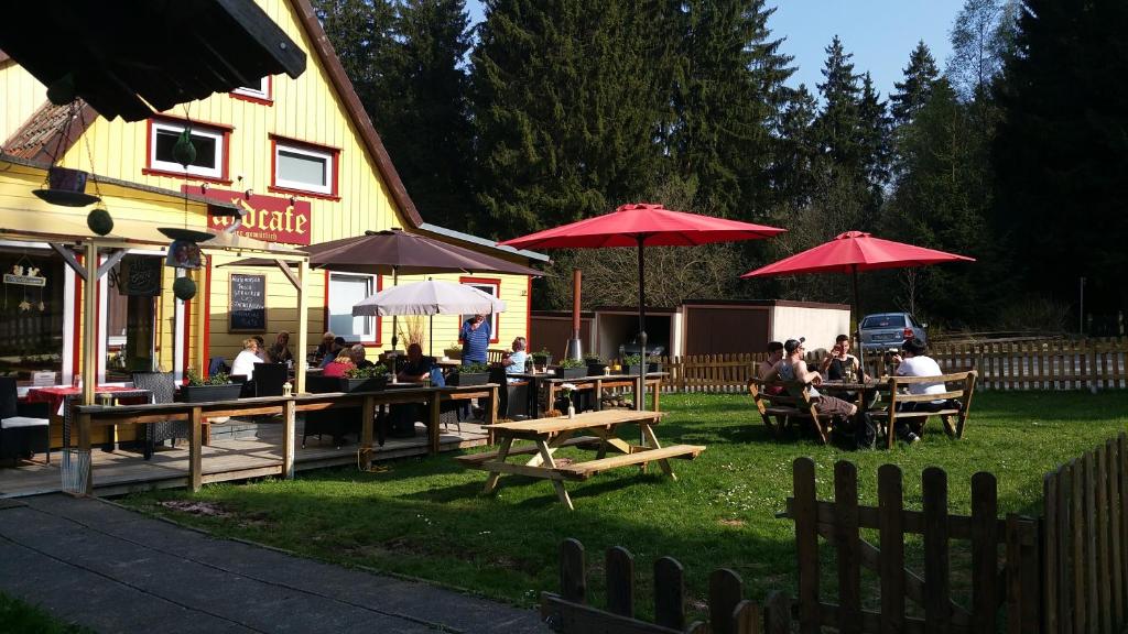 a group of people sitting at tables under umbrellas at B&B Waldcafe in Altenau