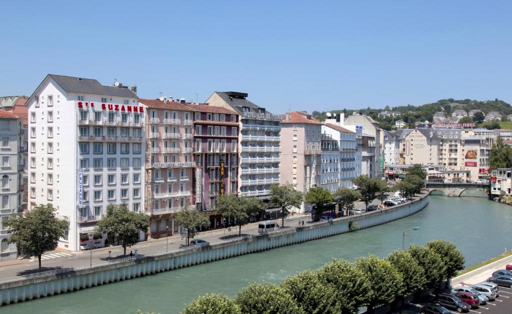 a river in a city with tall buildings and cars at Hôtel Sainte Suzanne in Lourdes