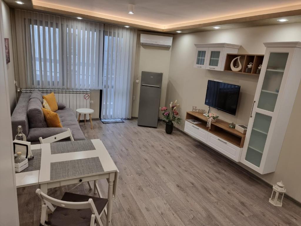 een woonkamer met een bank en een tv bij Flowers Apartment in Dobrich