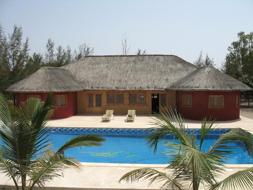 une maison avec une piscine en face de celle-ci dans l'établissement le baobab de nianing, à Nianing