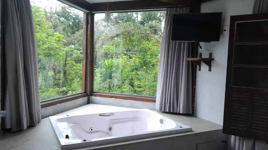 a bath tub in a bathroom with a large window at Pousada Canto da Lua in Nova Lima