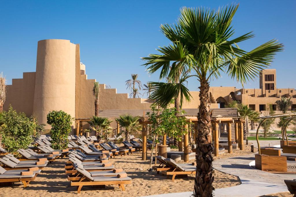 eine Palme und Liegestühle vor einem Gebäude in der Unterkunft Terra Solis Dubai in Dubai
