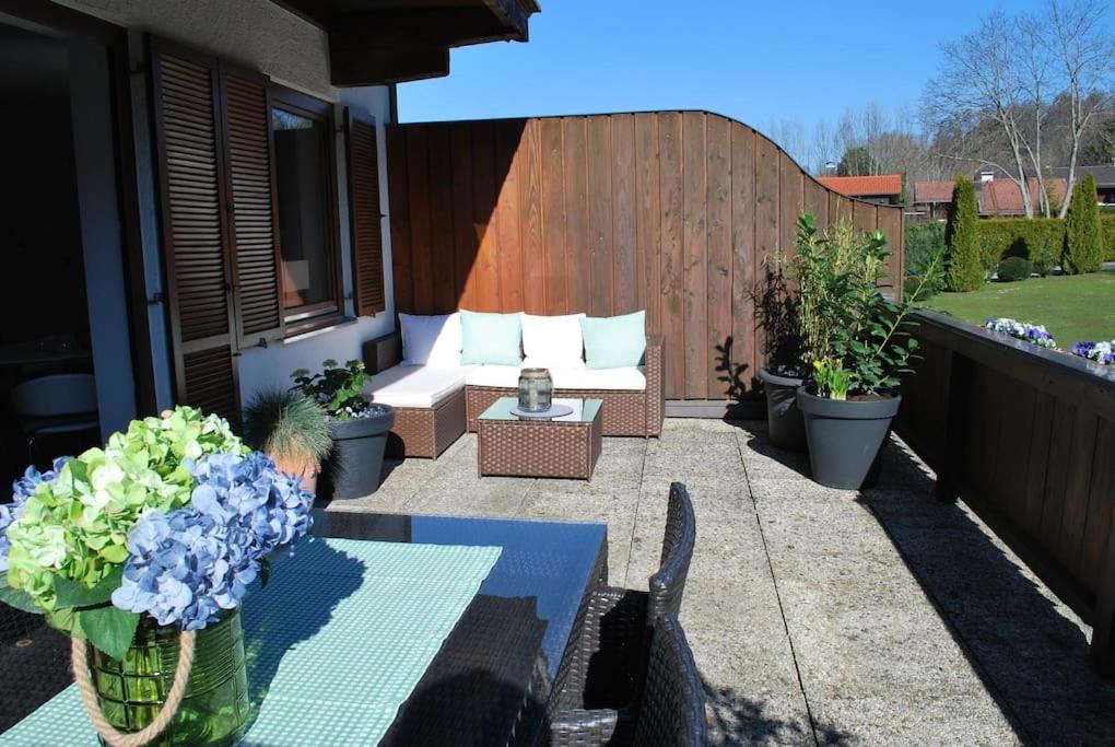 une terrasse avec un canapé, une table et des fleurs dans l'établissement Wohnung direkt am Tegernsee mit XL-Terrasse, à Gmund am Tegernsee