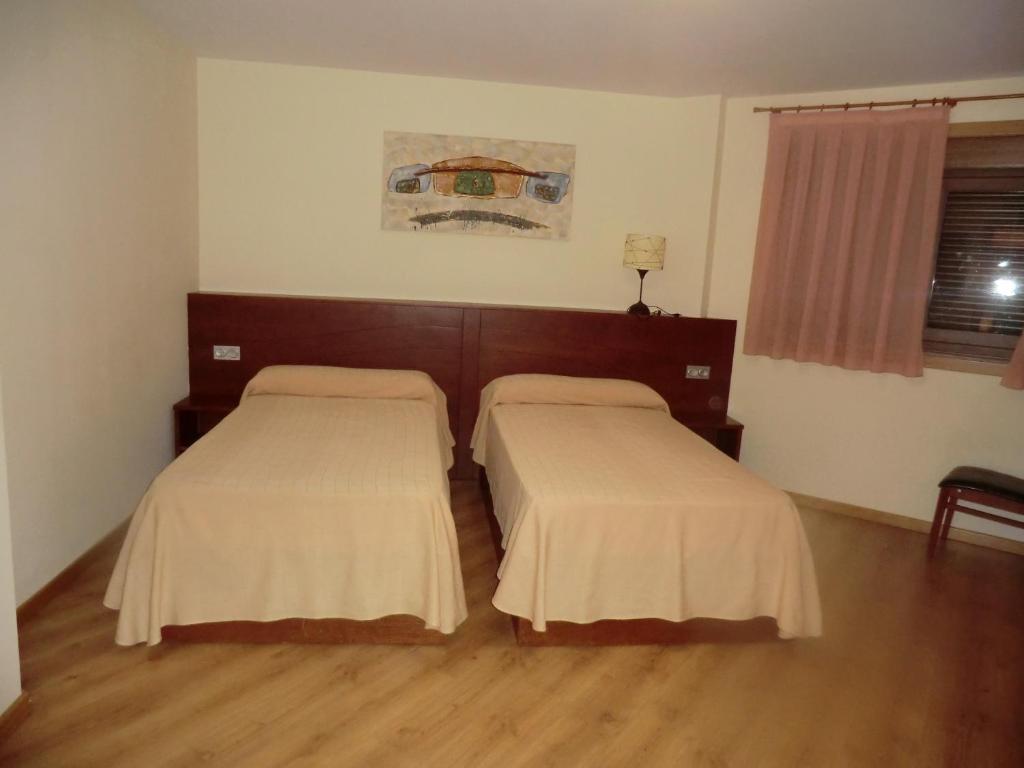 two beds in a room with wooden floors at Hotel Naval do Espiño in Donsión