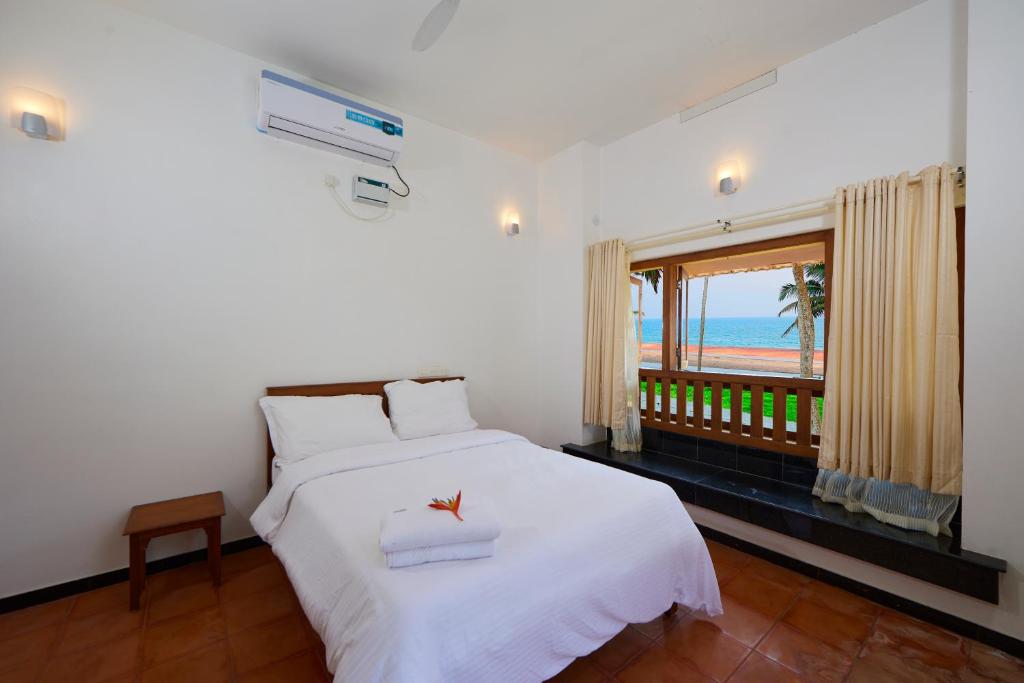 a bedroom with a bed with a view of the ocean at Paraikal Beach Resort in Kolachel