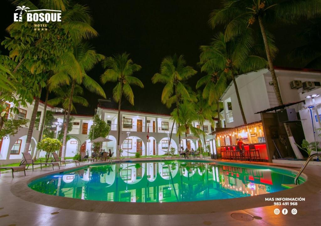 uma piscina em frente a um edifício com palmeiras em Hotel El Bosque em Jaén