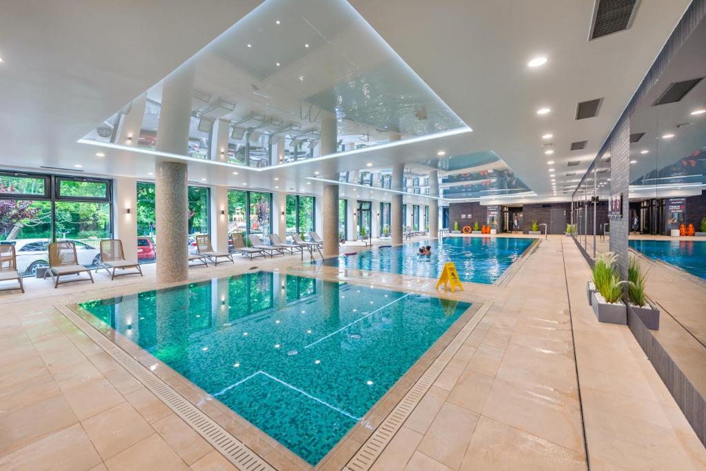 a large indoor pool with blue water in a building at Apartament Lux Tukan A315 Nadmorskie Tarasy - Holiday City in Kołobrzeg