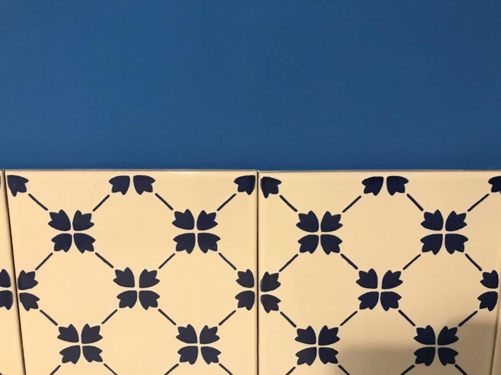 a white tiled wall with black flowers on it at B&B Via dell'Azzurra in Bari